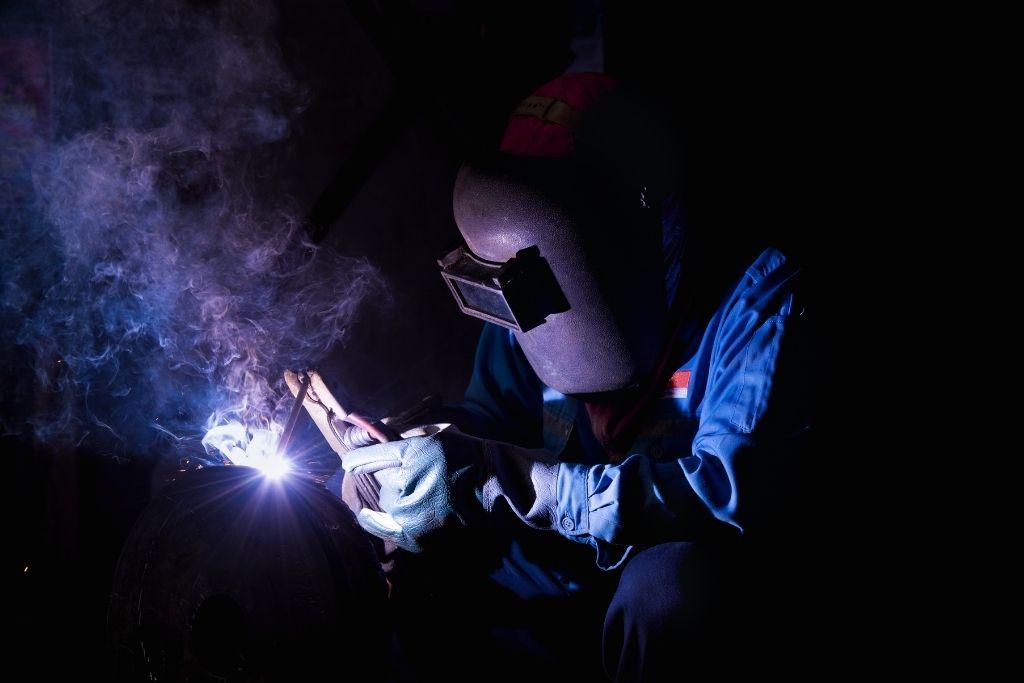 Welder performing SMAW with stick welder.